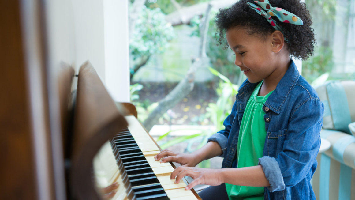 Adorable girl playing piano at home Teach Children to Love God